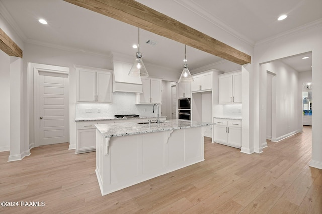 kitchen featuring white cabinets, a center island with sink, appliances with stainless steel finishes, and light hardwood / wood-style flooring