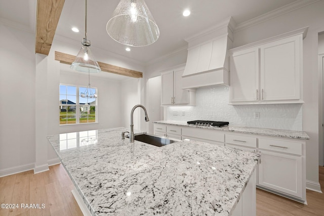 kitchen with white cabinetry, sink, pendant lighting, a spacious island, and light wood-type flooring