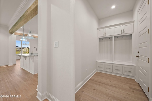 mudroom with light hardwood / wood-style floors, ornamental molding, and sink