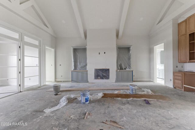 unfurnished living room with a fireplace, beam ceiling, and high vaulted ceiling