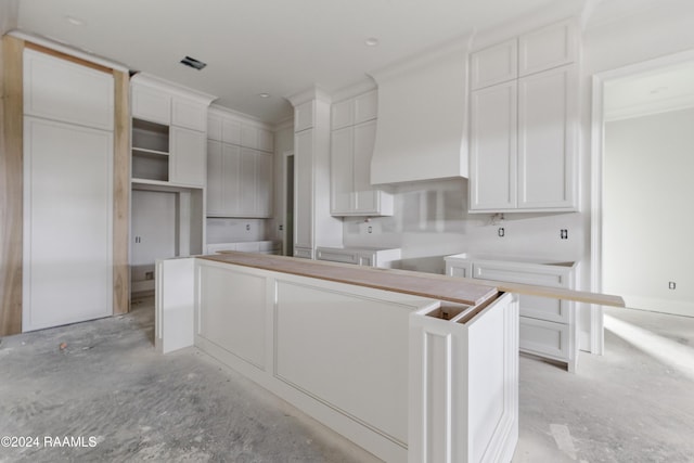 kitchen with white cabinets, a center island, and crown molding