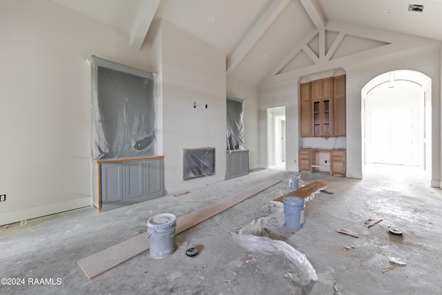 unfurnished living room with beam ceiling and high vaulted ceiling