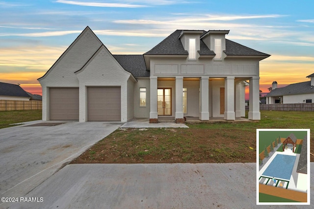 view of front of property with a garage, covered porch, and a yard