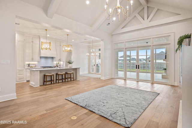 interior space with a notable chandelier, beamed ceiling, high vaulted ceiling, and light wood-type flooring