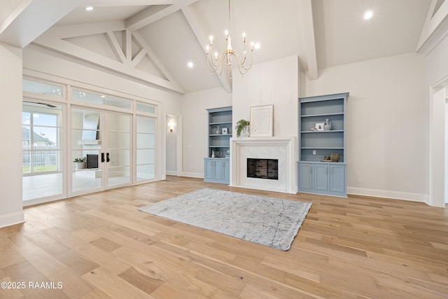 unfurnished living room with a high end fireplace, baseboards, beamed ceiling, light wood-style floors, and high vaulted ceiling