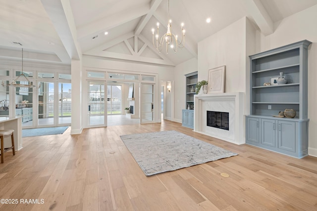 unfurnished living room featuring beam ceiling, a notable chandelier, high vaulted ceiling, light wood-style flooring, and a fireplace