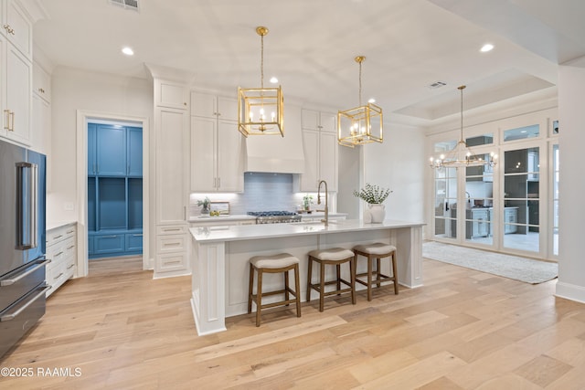 kitchen with backsplash, appliances with stainless steel finishes, white cabinets, and light wood-style floors