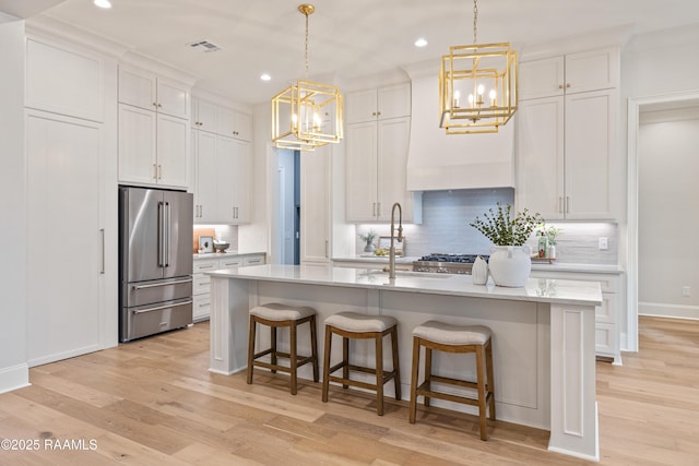 kitchen featuring an inviting chandelier, light wood-style flooring, high end refrigerator, and light countertops