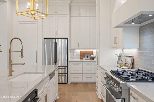 kitchen featuring white cabinets, high end appliances, custom range hood, and a sink