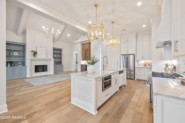 kitchen with light wood finished floors, an inviting chandelier, custom exhaust hood, stainless steel appliances, and a sink