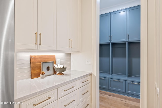 bar with decorative backsplash, light wood-style floors, and crown molding