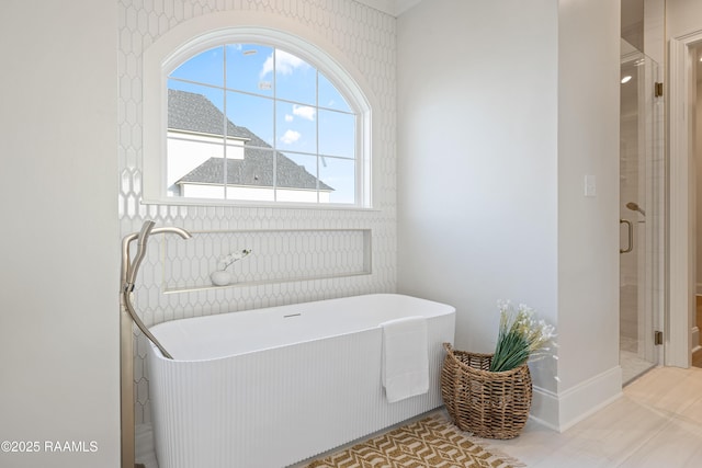 full bathroom with tile patterned flooring, a soaking tub, and a stall shower