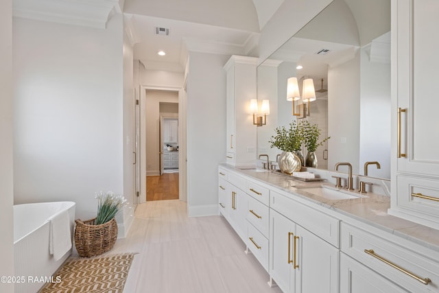 full bathroom with double vanity, a freestanding tub, baseboards, and a sink