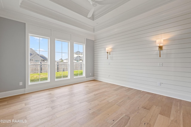 spare room featuring a tray ceiling, baseboards, light wood-style flooring, and a ceiling fan