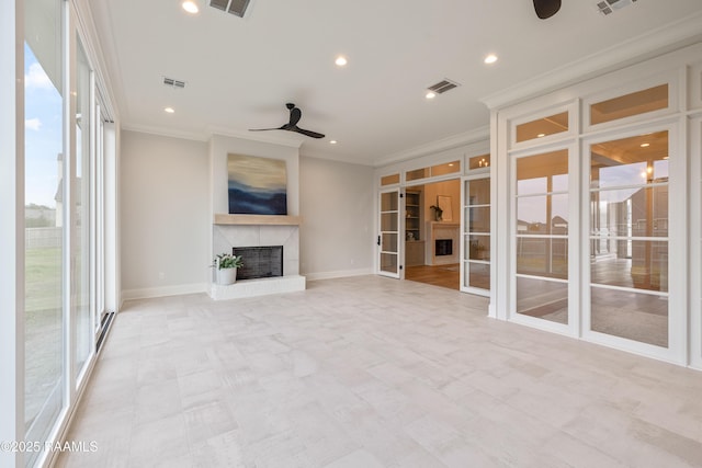 unfurnished living room with visible vents, a fireplace with raised hearth, french doors, crown molding, and ceiling fan