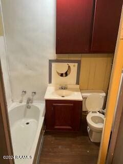 bathroom with a bathing tub, vanity, toilet, and wood-type flooring