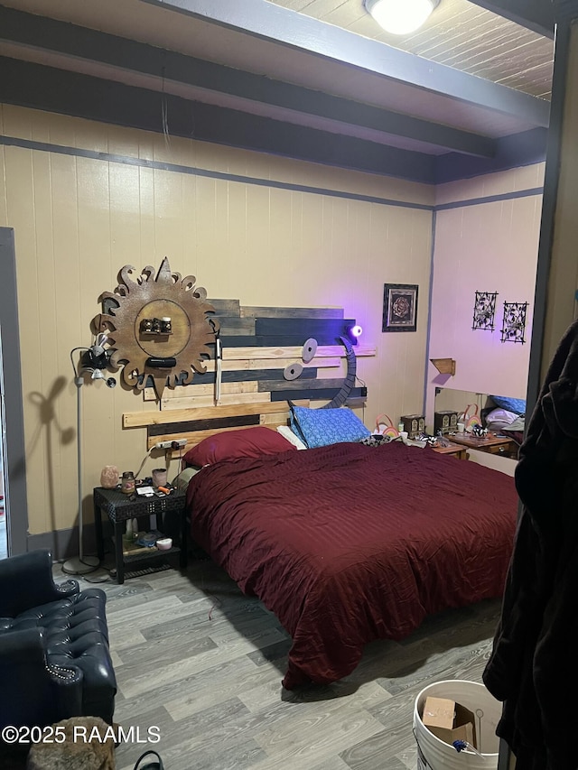 bedroom featuring wood walls, beamed ceiling, and wood-type flooring