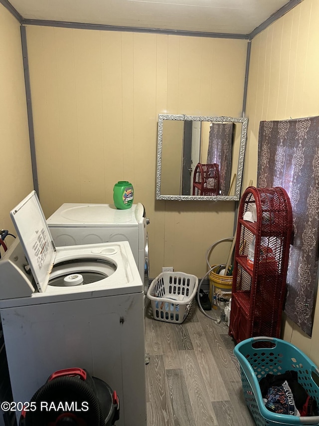 laundry area featuring washing machine and dryer, wood walls, and hardwood / wood-style floors