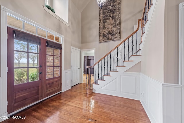 entryway featuring wood-type flooring, a towering ceiling, and french doors