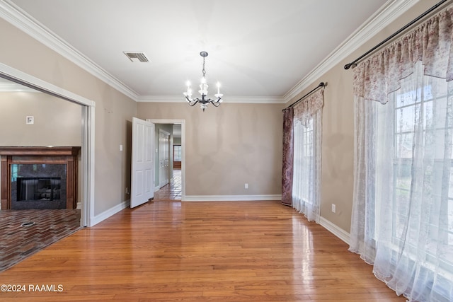 unfurnished dining area featuring a notable chandelier, ornamental molding, and light hardwood / wood-style flooring