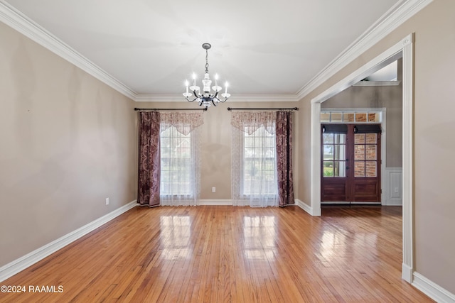 unfurnished dining area featuring hardwood / wood-style flooring, ornamental molding, french doors, and a chandelier