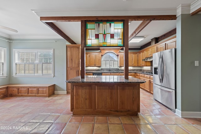 kitchen with dark stone countertops, crown molding, a center island, and appliances with stainless steel finishes
