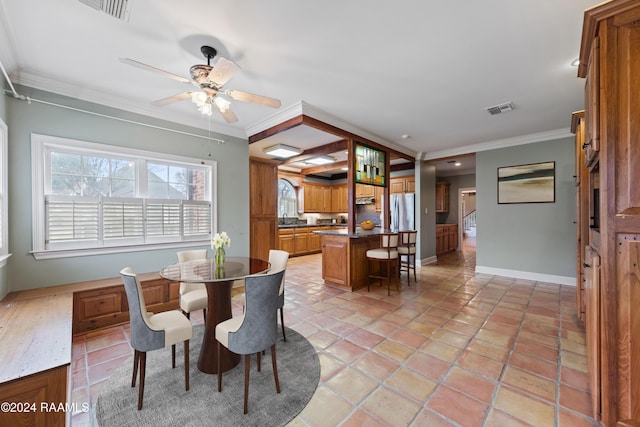 tiled dining space featuring ceiling fan, sink, and crown molding