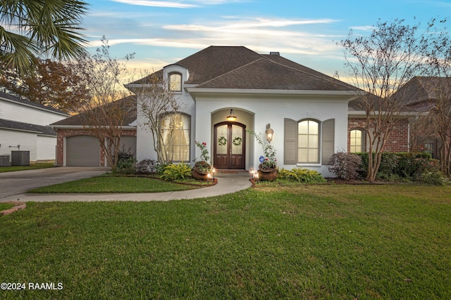 view of front of property featuring central air condition unit, a yard, and french doors