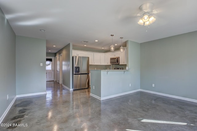 kitchen with white cabinets, a kitchen breakfast bar, appliances with stainless steel finishes, decorative light fixtures, and kitchen peninsula