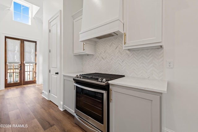 kitchen featuring white cabinetry, french doors, dark hardwood / wood-style floors, custom range hood, and stainless steel range with gas stovetop