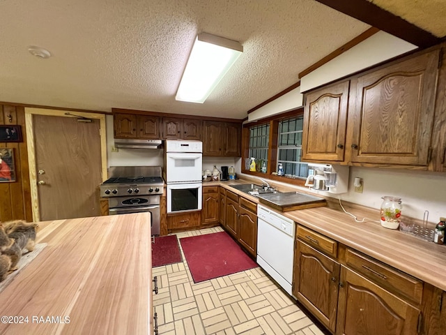 kitchen with lofted ceiling, white appliances, sink, ornamental molding, and a textured ceiling