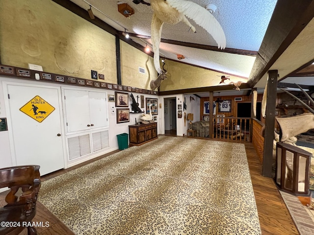 interior space with beamed ceiling, wood-type flooring, a textured ceiling, and high vaulted ceiling