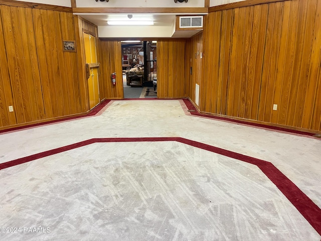 basement featuring light colored carpet and wood walls