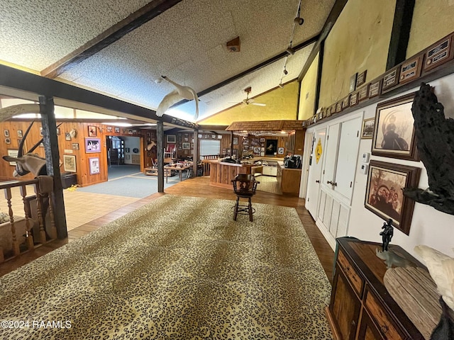 recreation room featuring dark hardwood / wood-style flooring, a textured ceiling, ceiling fan, beam ceiling, and high vaulted ceiling