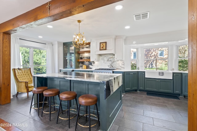 kitchen with pendant lighting, backsplash, white cabinets, a kitchen breakfast bar, and a chandelier