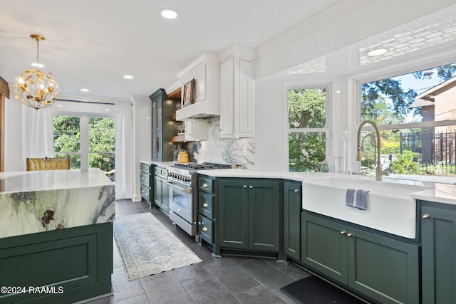 kitchen with white cabinets, sink, high end stove, tasteful backsplash, and decorative light fixtures