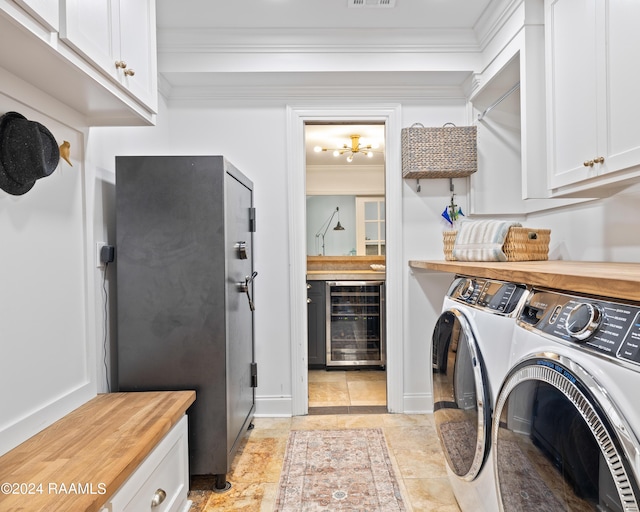 clothes washing area with cabinets, independent washer and dryer, ornamental molding, and wine cooler