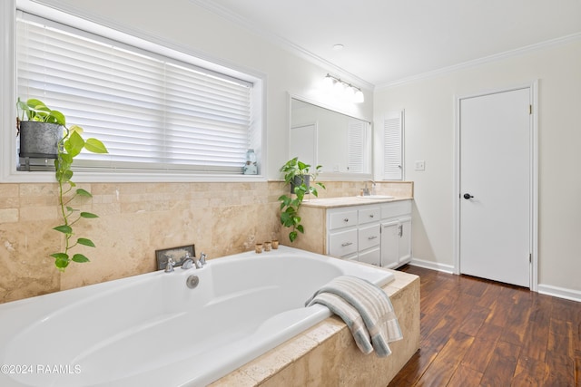 bathroom with hardwood / wood-style floors, vanity, crown molding, and tiled tub