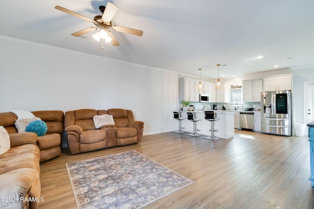 living room featuring light hardwood / wood-style flooring, ceiling fan, and crown molding