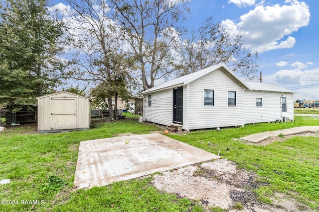 back of property featuring a lawn, a patio area, and a storage unit