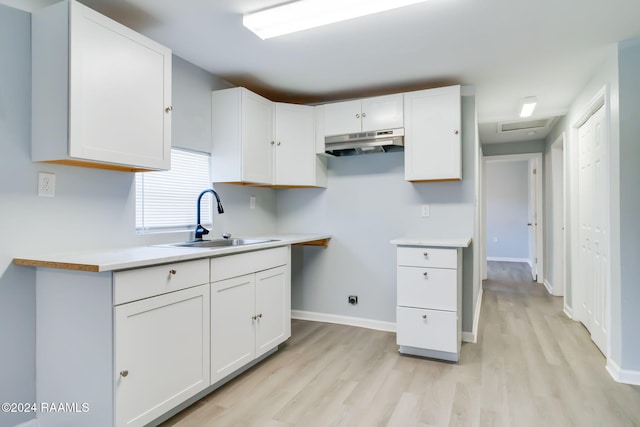 807 American Legion Dr, Rayne, LA 70578 - kitchen featuring under cabinet range hood, light wood-style flooring, white cabinetry, and light countertops