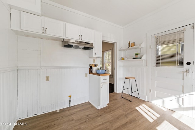 kitchen with butcher block counters, white cabinets, light hardwood / wood-style floors, and ornamental molding