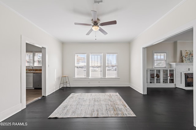 interior space featuring a brick fireplace, ceiling fan, dark wood-type flooring, crown molding, and sink