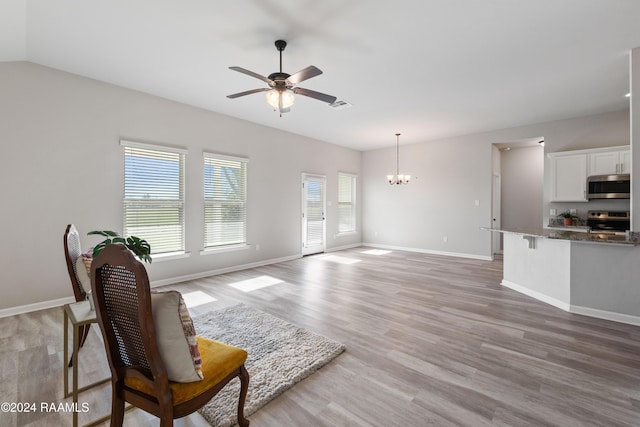 living room with hardwood / wood-style floors, ceiling fan with notable chandelier, and vaulted ceiling