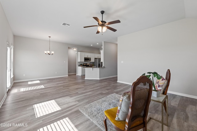 living room with ceiling fan with notable chandelier and light wood-type flooring