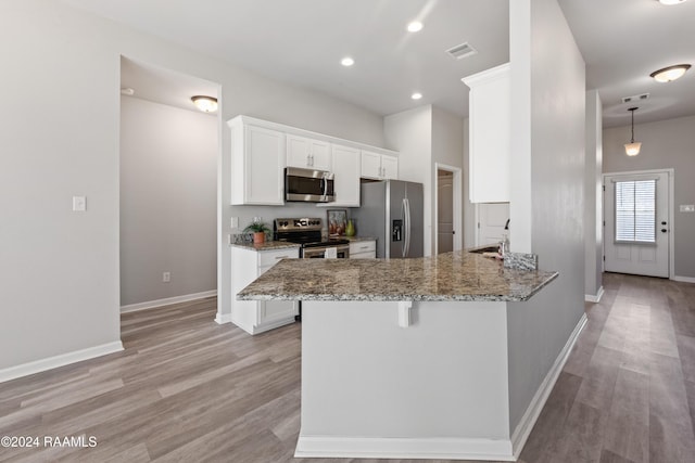 kitchen featuring stainless steel appliances, light stone counters, kitchen peninsula, white cabinets, and light wood-type flooring