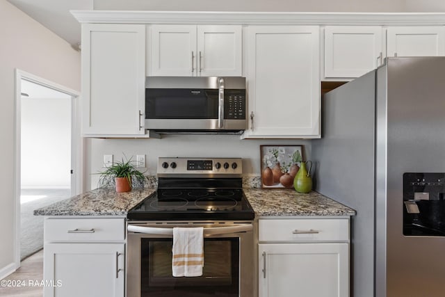 kitchen with light stone counters, white cabinetry, and appliances with stainless steel finishes