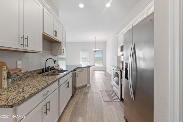 kitchen with appliances with stainless steel finishes, sink, pendant lighting, light hardwood / wood-style flooring, and white cabinetry