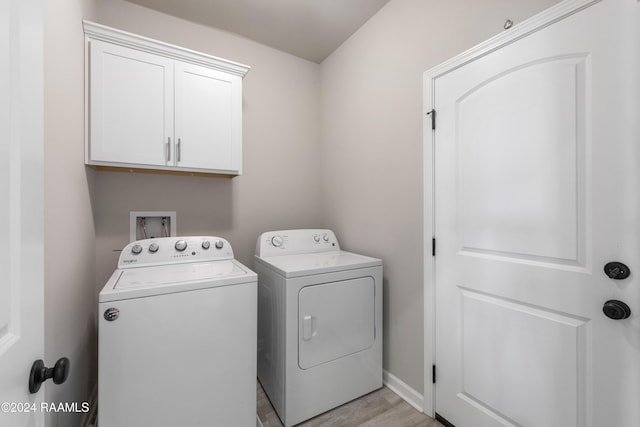 washroom featuring cabinets, light hardwood / wood-style floors, and washer and clothes dryer