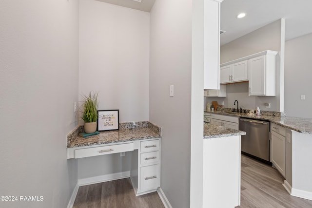 kitchen with stainless steel dishwasher, white cabinets, light stone countertops, and light wood-type flooring